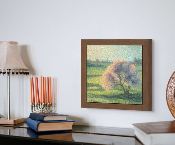 Framed pointillism painting of a blossoming tree in a green meadow, created with colorful dots that convey vibrancy and movement, displayed in a cozy home interior