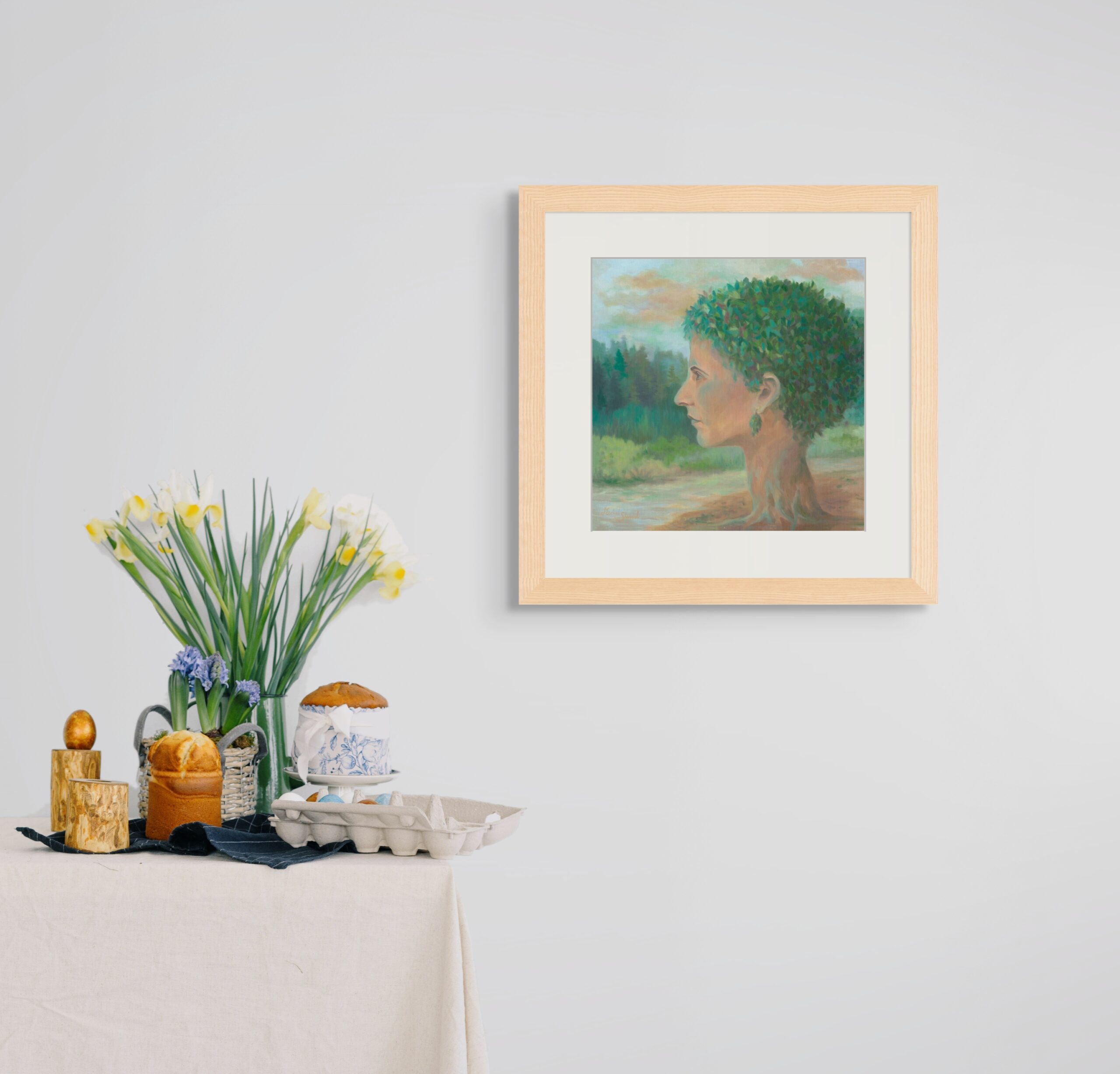 Surrealist self-portrait painting of a woman’s profile merging with a tree, symbolizing nature, identity, and transformation, displayed in a light wooden frame on a modern wall.